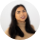 A woman with long, dark wavy hair smiling at the camera against a plain white background.