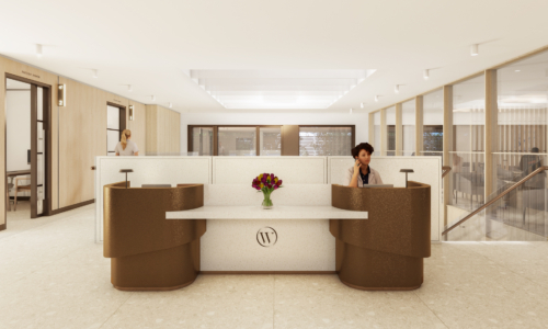 A modern hotel or office lobby reception desk with curved brown seating, white marble countertop, and a vase of purple tulips, staffed by a receptionist in a bright, minimalist space with glass partitions and contemporary lighting.