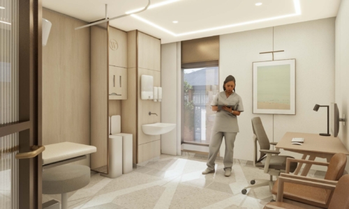 A healthcare professional in scrubs stands in a modern medical office or patient room, reading from a tablet while surrounded by contemporary furniture, built-in cabinetry with a sink area, and warm wood and neutral tones throughout the space.