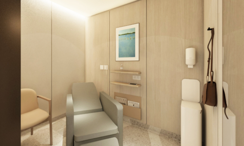 A modern medical examination room with light wood paneling, featuring a reclining examination chair, a regular chair for visitors, built-in storage cabinets, and medical equipment mounted on the walls.