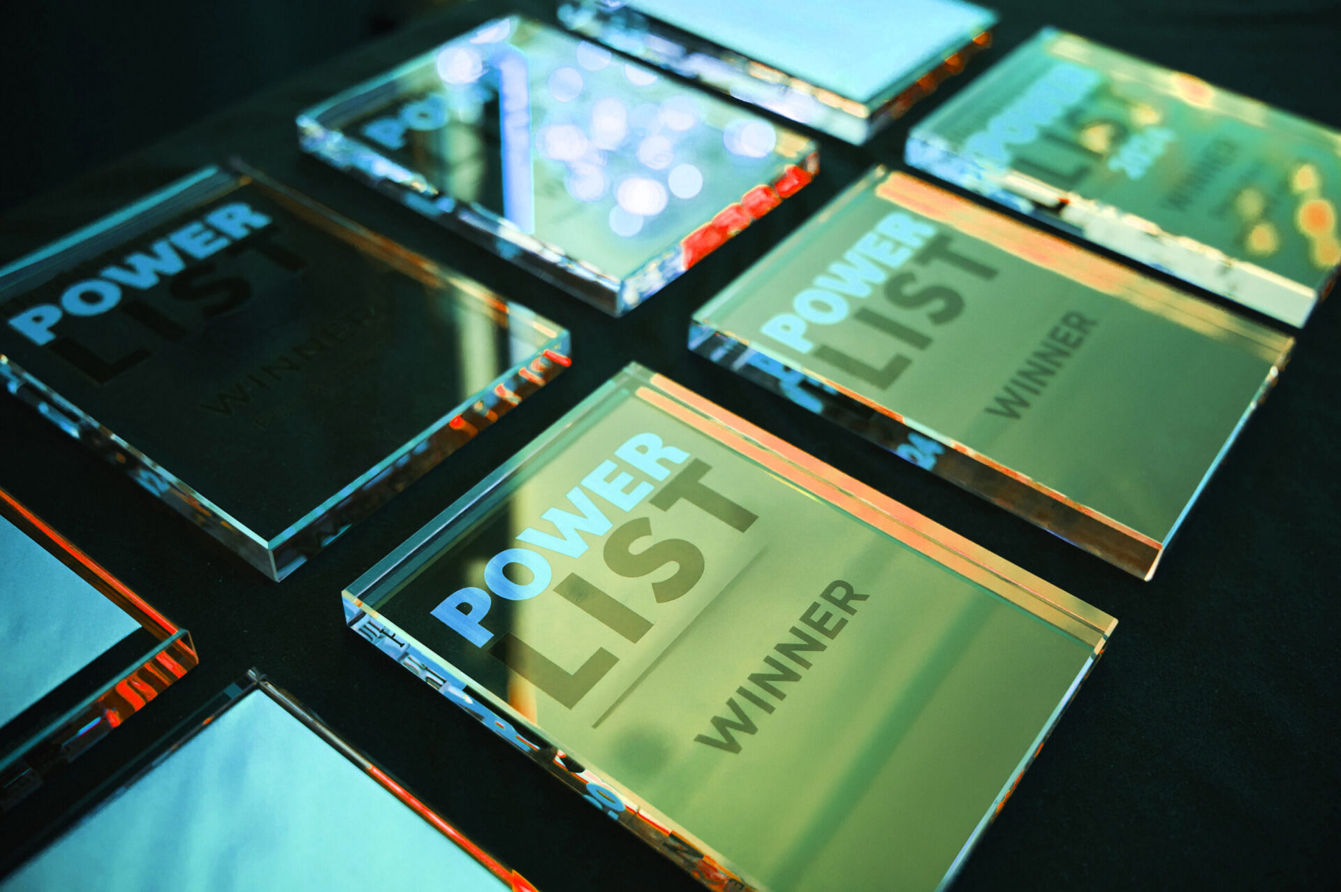 Multiple crystal or glass awards arranged on a dark surface, with 